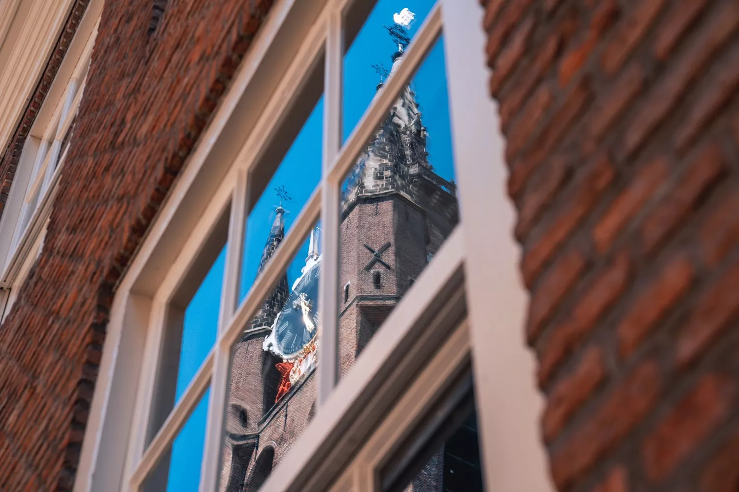 De Oude Kerk, weerspiegeld in een raam van een woning in Delft.
