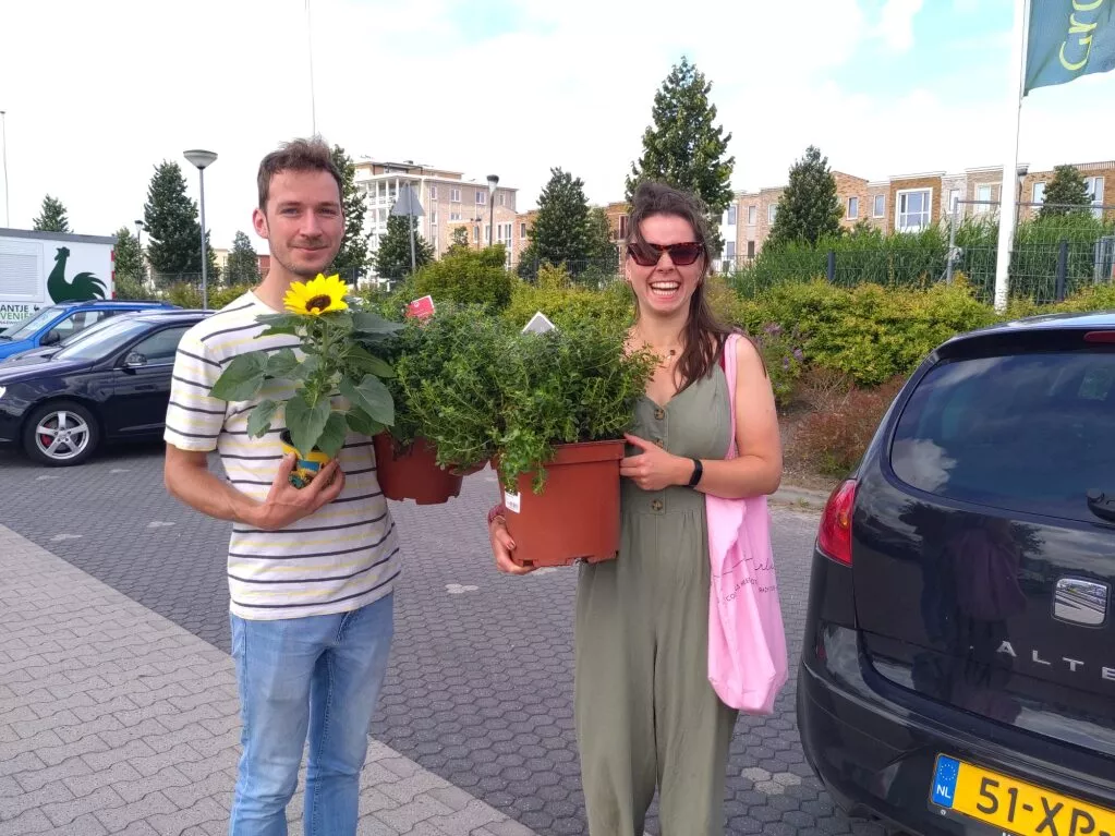 man en vrouw met in hun handen planten op de parkeetplaats van het tuincentrum.