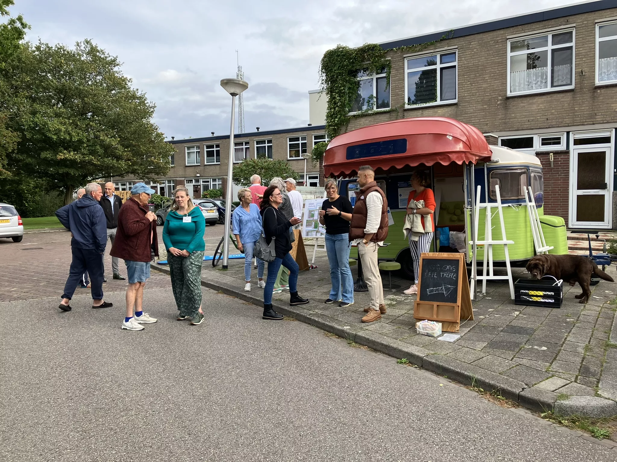 meerdere mensen in gesprek bij een caravan op de straat