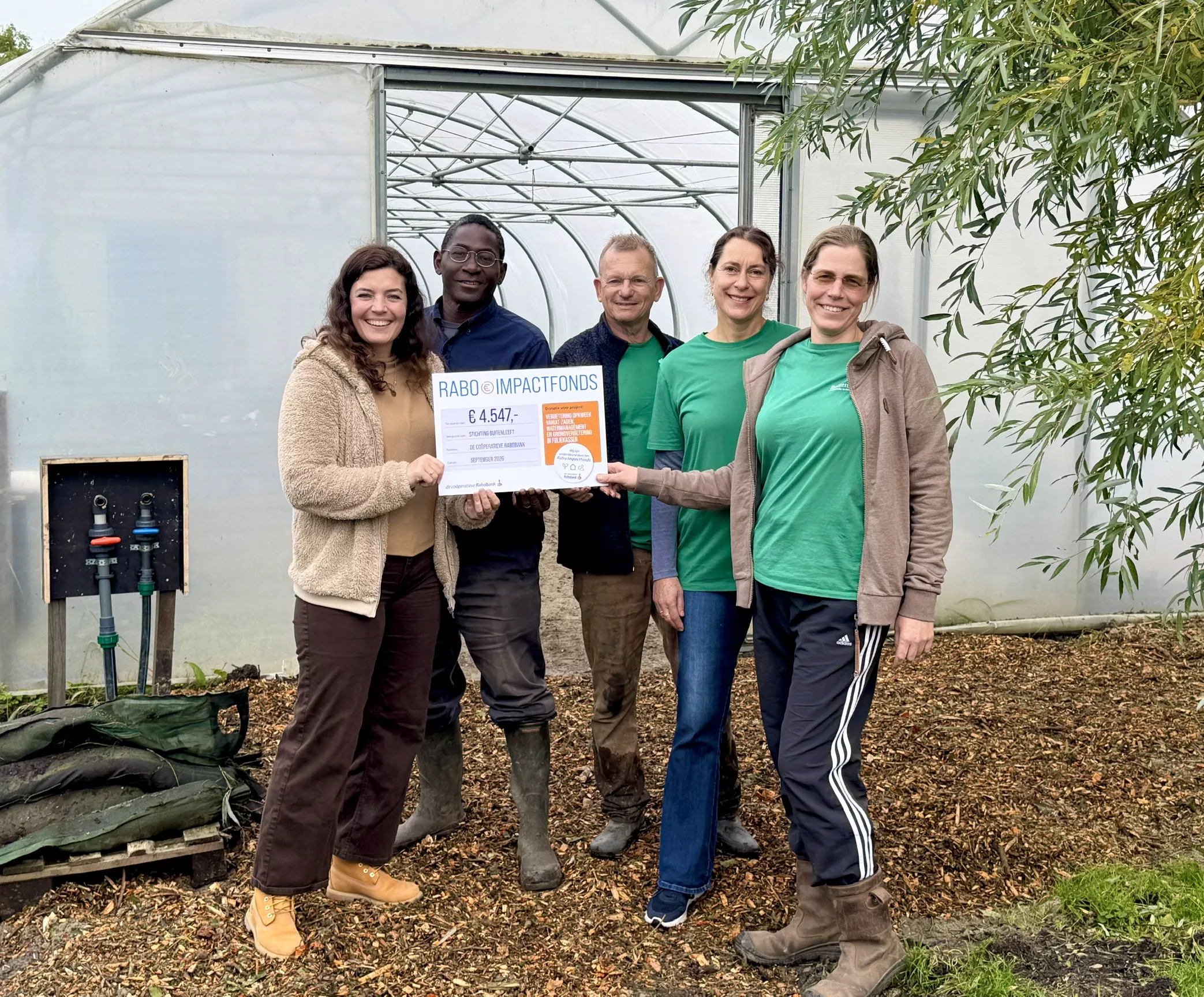 Vijf personen presenteren een Rabo Impactfonds-cheque van 4.547 euro voor een foliekas van stadstuinderij Buitenleeft.